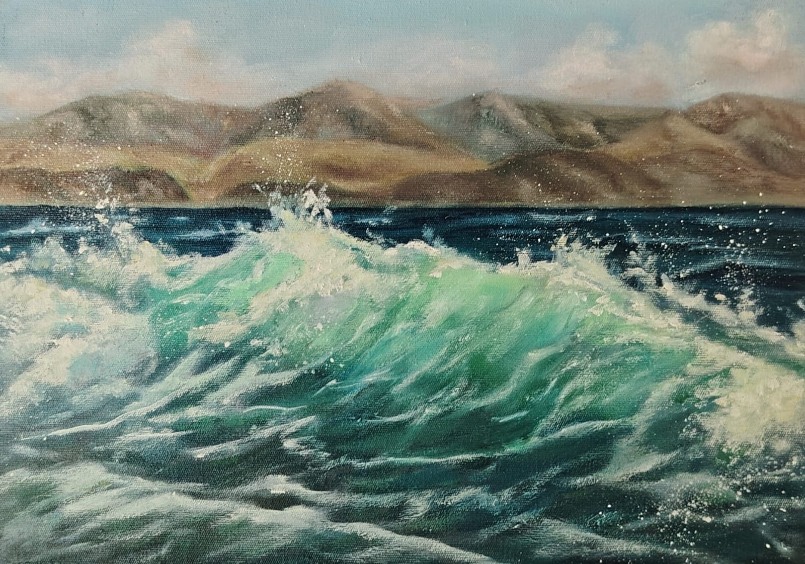 Turquoise wave with mountains behind